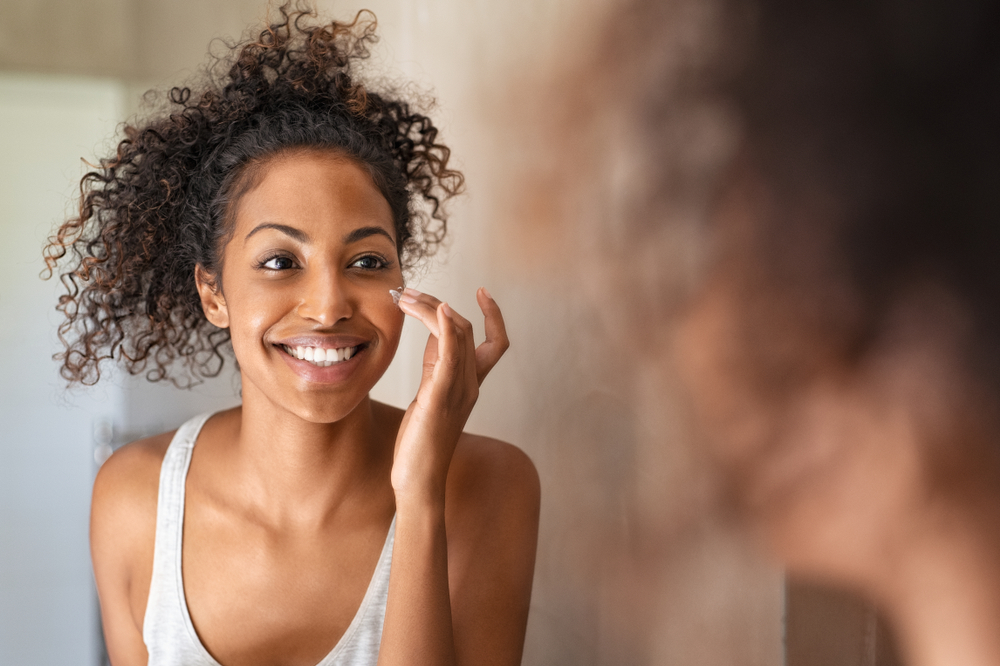 Young Woman Applying Moisturising Cream On Cheeks