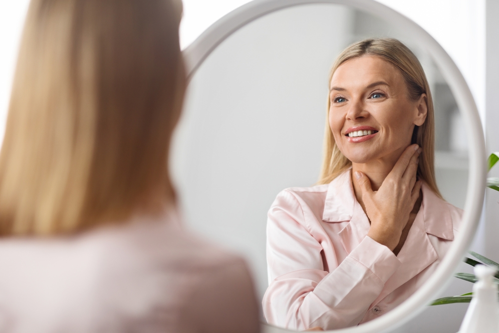 Beautiful Middle Aged Woman Looking At Mirror And Touching Her Neck